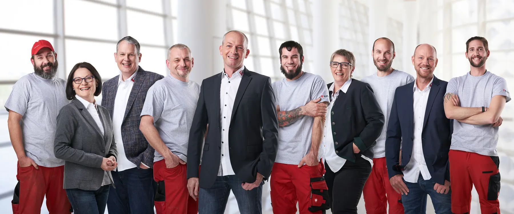 Gut gelauntes zehnköpfiges Team aus Handwerk und Büro, Gruppenfoto in heller Ausstellungshalle
