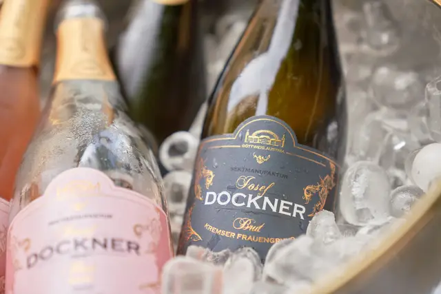 Zwei Sektflaschen der Sektmanufaktur Josef Dockner im Eiskübel, beschlagenes Glas und goldene Etiketten