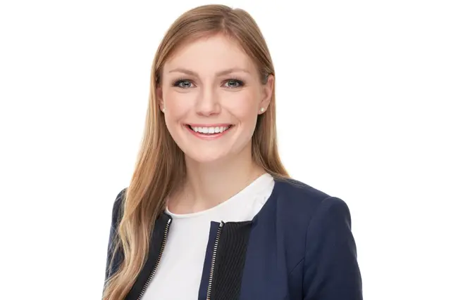 Strahlend lächelnde junge Frau mit langen blonden Haaren im dunkelblauen Blazer, Bewerbungsfoto vor weißem Studiohintergrund