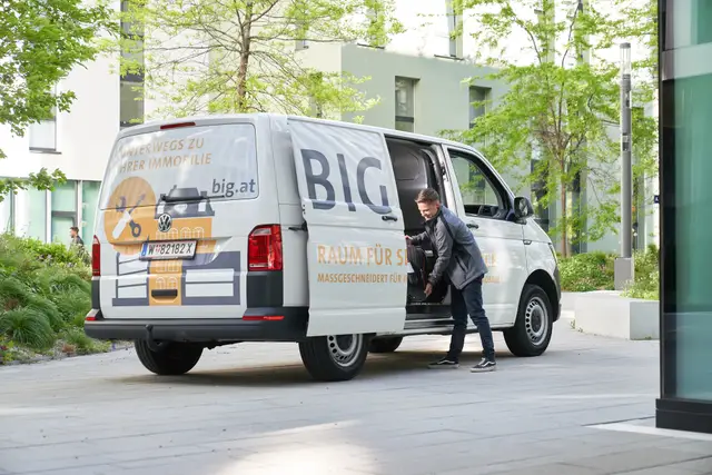 Servicetechniker belädt Firmenbus im begrünten Innenhof – Mitarbeiterfoto direkt vor Ort im Einsatz