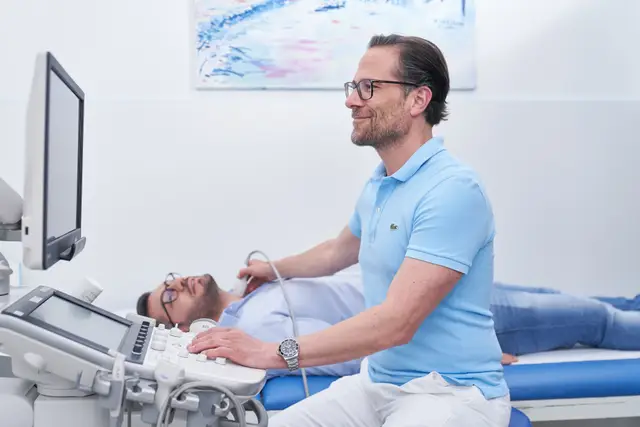 Arzt bei der Ultraschalluntersuchung eines Patienten in heller, moderner Ordination