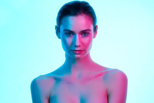 Beauty-Portrait einer Frau in blauem und pinkem Farblicht vor türkisem Hintergrund, moderne Werbefotografie