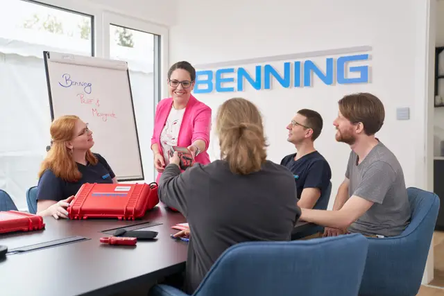 Teambesprechung am Konferenztisch: Kollegin präsentiert vier Mitarbeitenden ein Messgerät – Employer-Branding-Foto