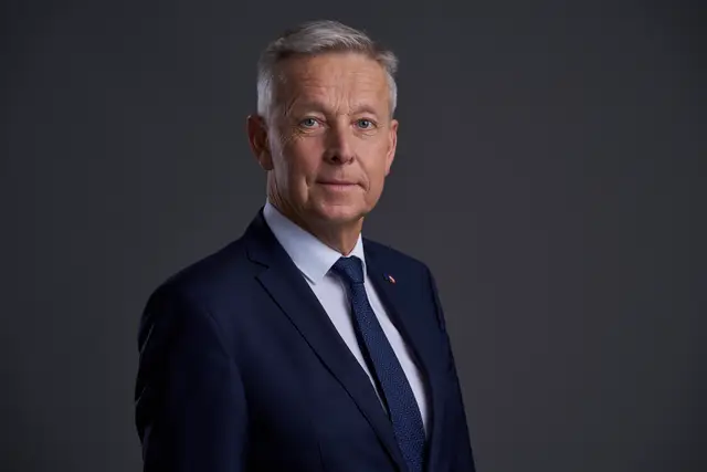 Seriöses Politiker-Portrait im dunkelblauen Anzug mit Krawatte vor dunkelgrauem Studiohintergrund