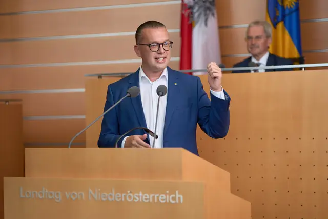 Abgeordneter mit Brille gestikuliert engagiert am Rednerpult des Landtags – authentische Pressefotografie