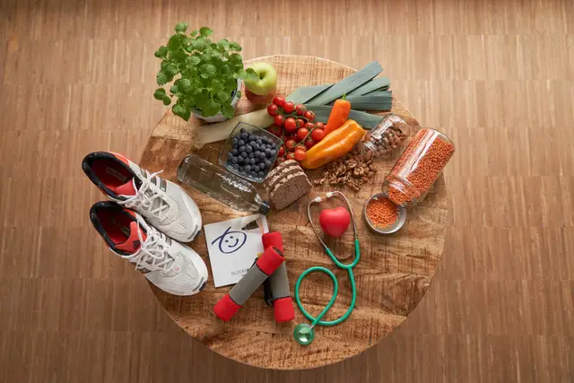 Stillleben zum Thema gesunder Lebensstil: Laufschuhe, Hanteln, Stethoskop, Gemüse und Hülsenfrüchte