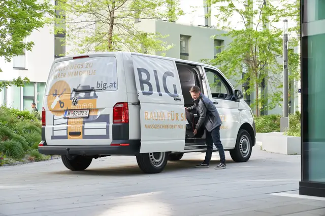 Servicetechniker belädt seinen Transporter vor einem Bürogebäude, Arbeitsalltag in der Gebäudeverwaltung