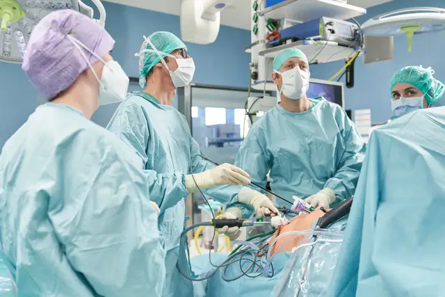 Chirurgenteam bei einer laparoskopischen Operation im OP-Saal, konzentrierter Blick auf den Monitor