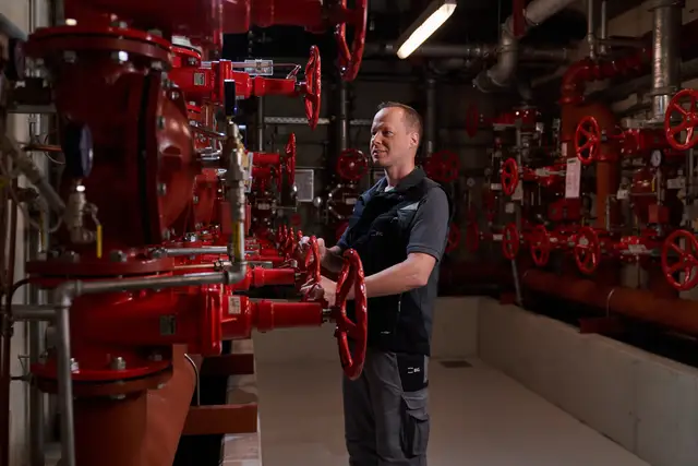 Techniker prüft die roten Ventile der Sprinkleranlage im Technikkeller – Arbeitsalltag im Brandschutz