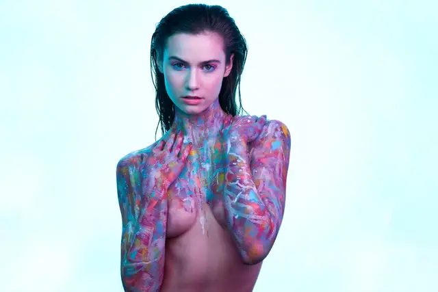 Model mit bunt bemalten Armen und Schultern in kühlem Studiolicht, farbstarke Bodypainting-Inszenierung